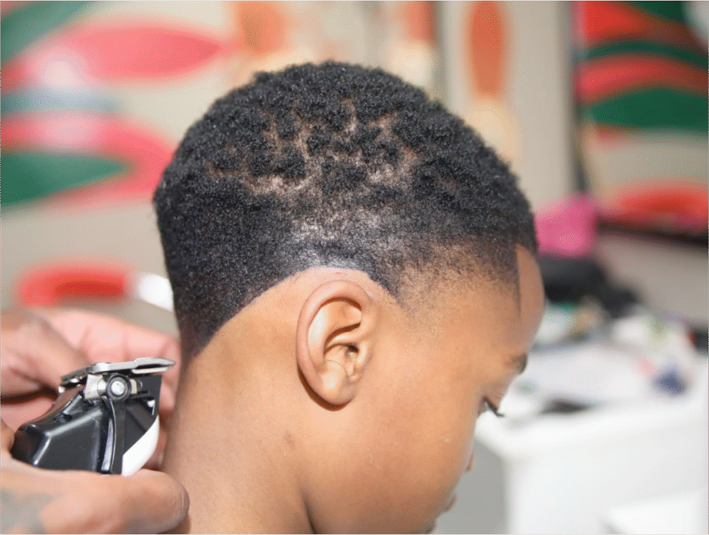 A friendly stylist giving a boy a neat kids' haircut at our Soweto salon, with a gentle wash and style.
