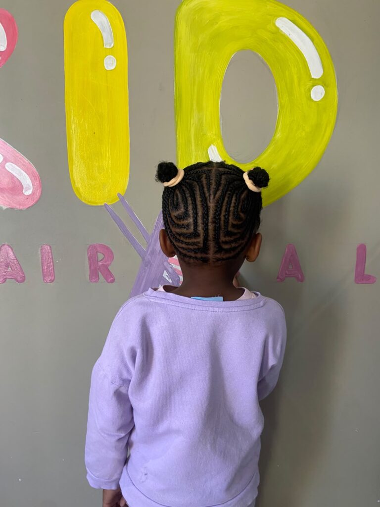 Bold, colourful kids hairstyle with playful accessories at Melza Kids Hair Salon